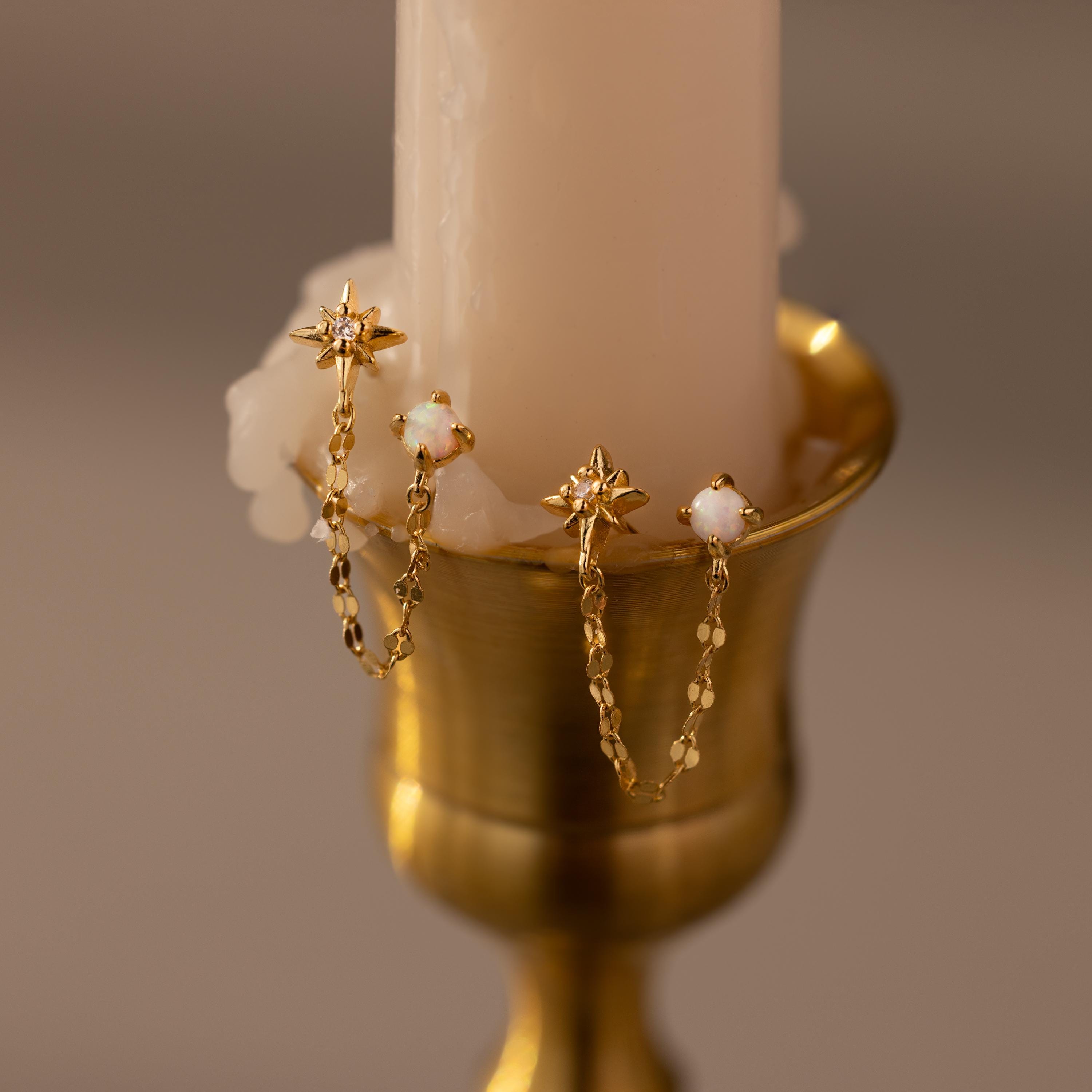Close up of our Opal & Star Duo Chain Studs against a beige candle
