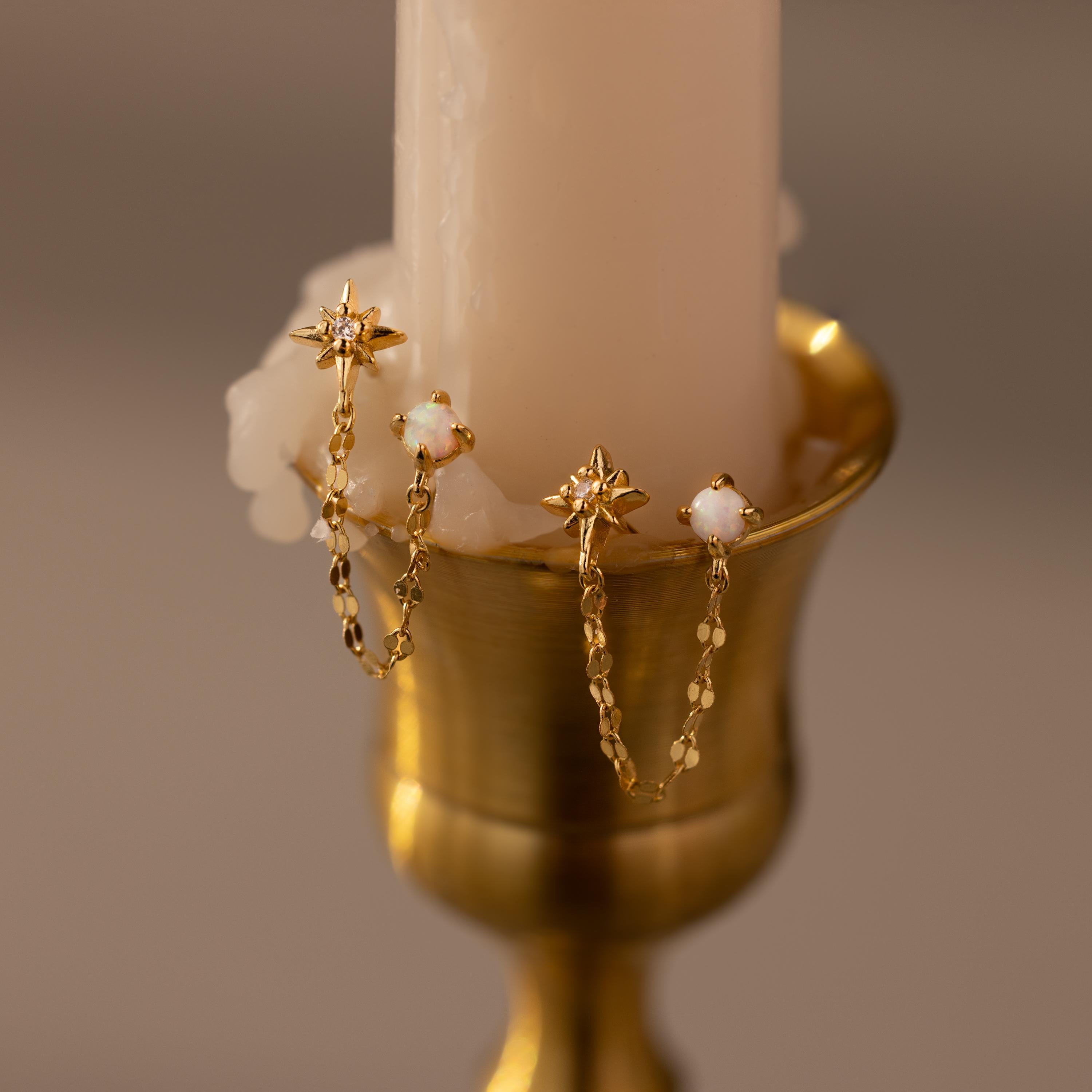 Opal & Star Duo Chain Studs in Gold against a beige candle