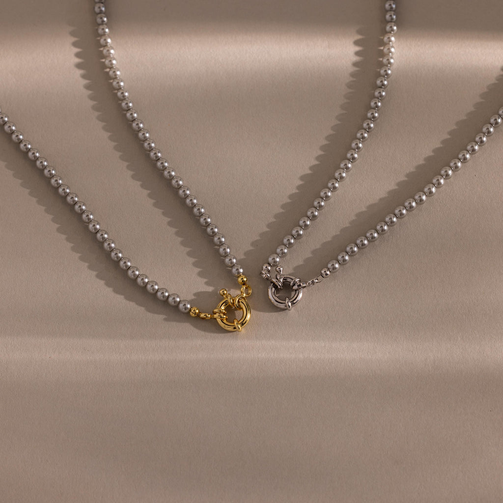 Flatlay of our Smoky Pearl Clasp Necklace in Gold and White Gold