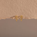 Photo of our Diamond Leaf Hoops in 18K Gold on a beige background