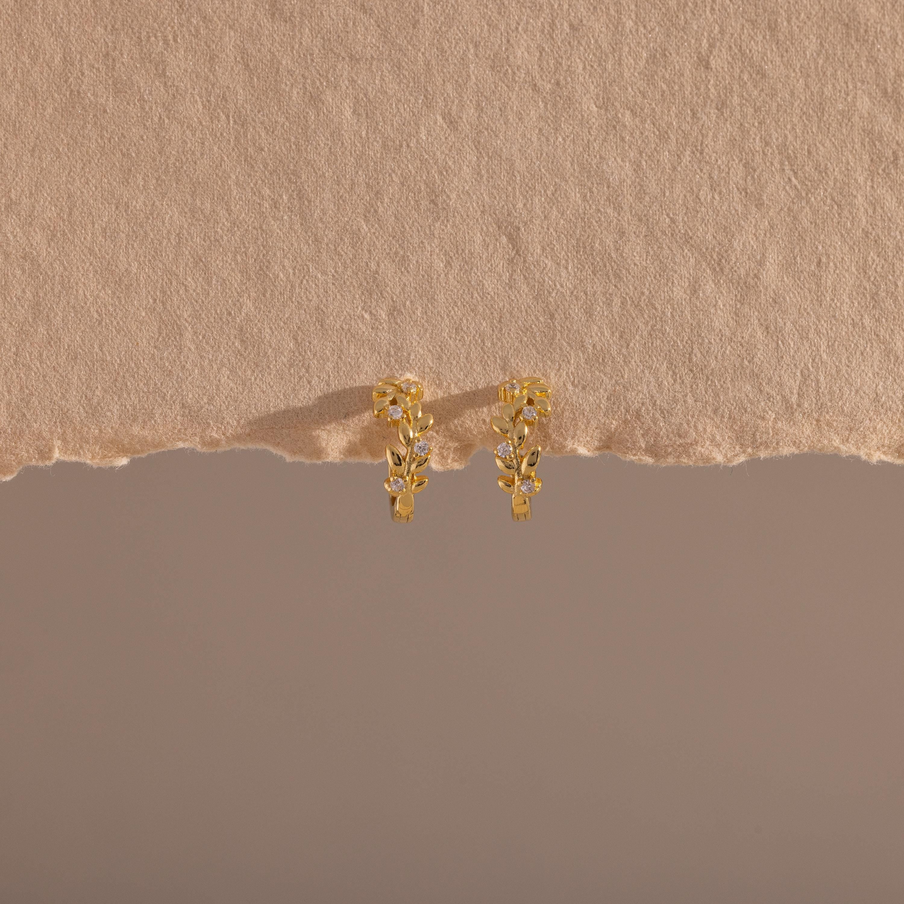 Photo of our Diamond Leaf Hoops in 18K Gold on a beige background