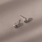 Pair of silver knot earrings on a beige background