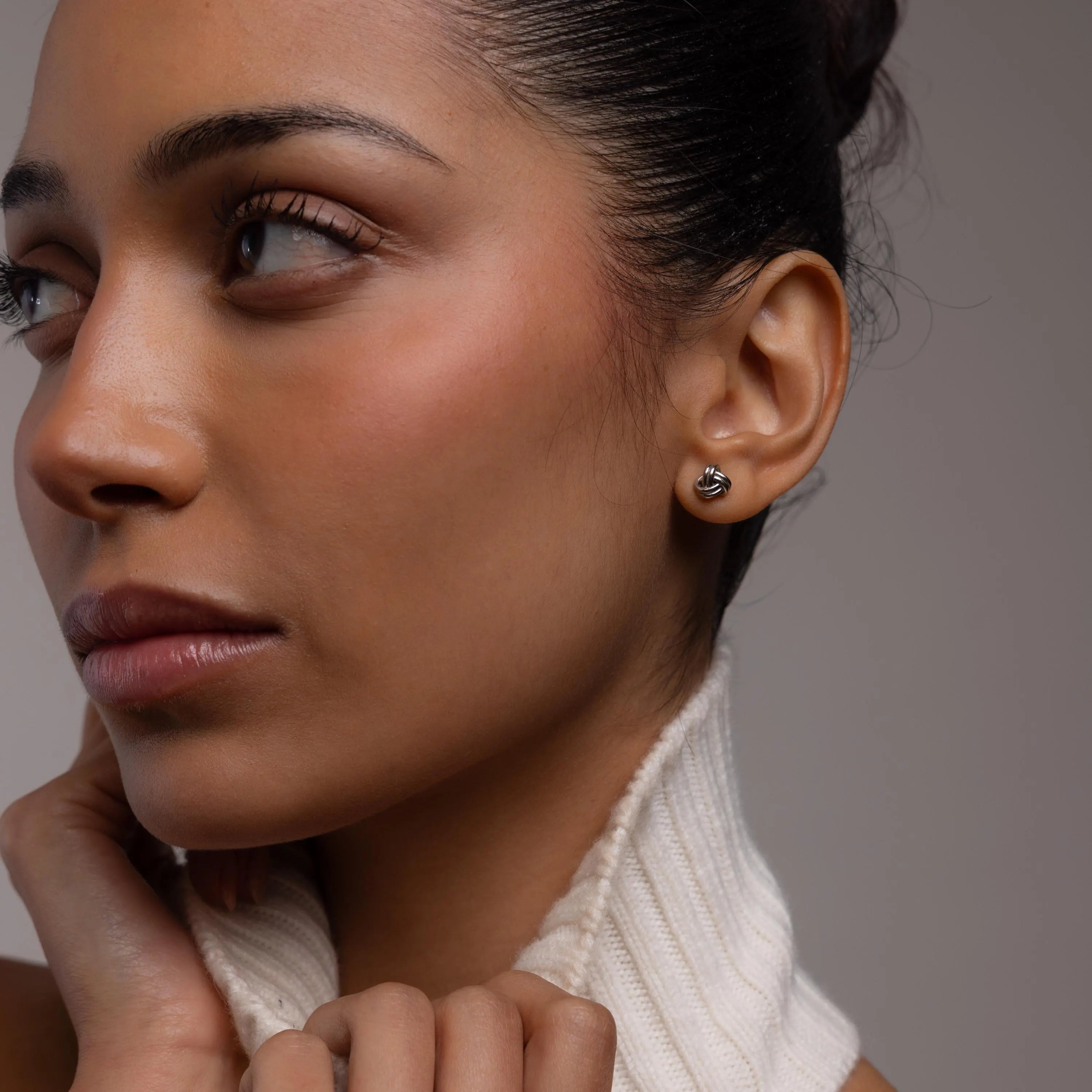 Close-up of a woman wearing silver knot earrings