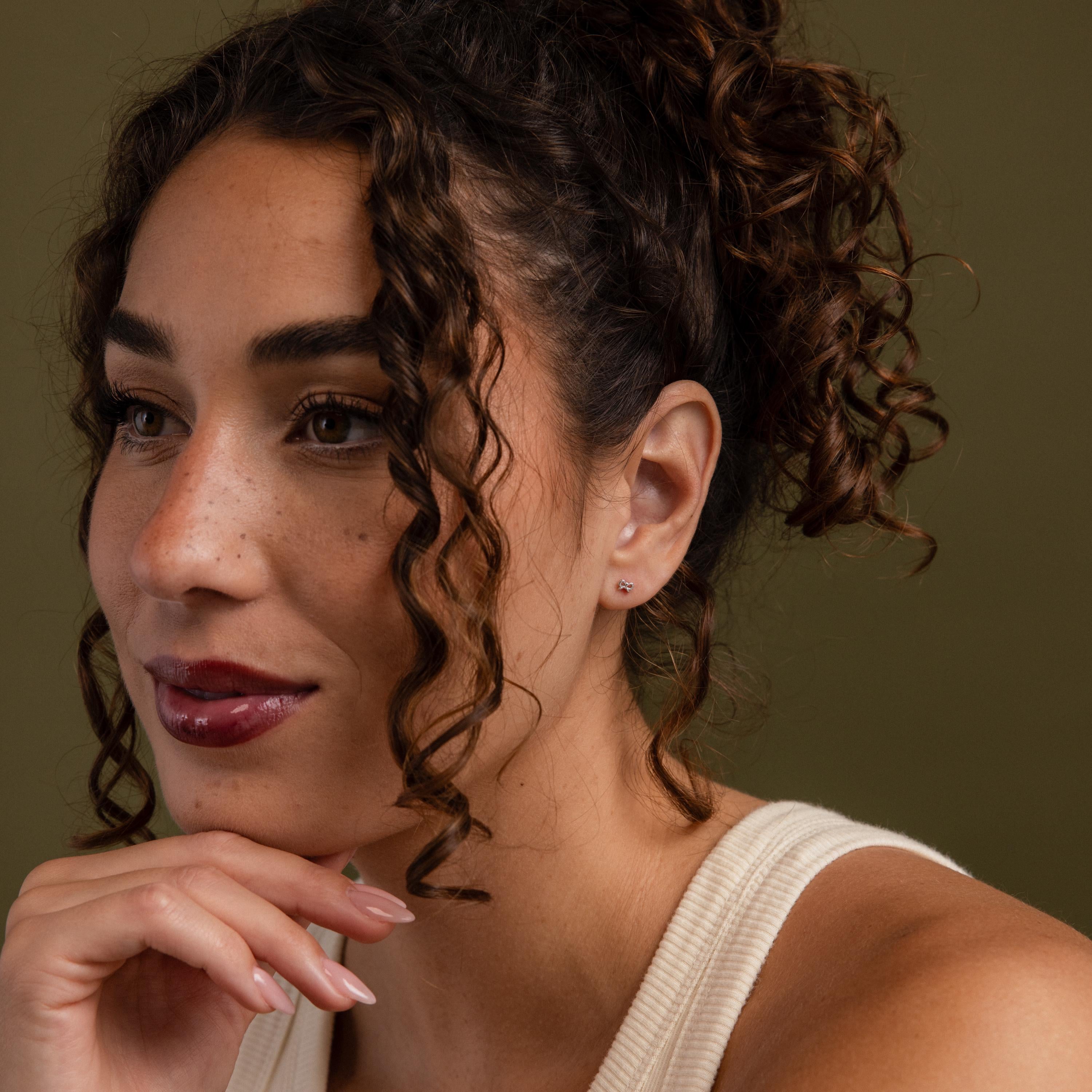 Faraway image of a model wearing our Tiny Bow Flatback Studs in Sterling Silver