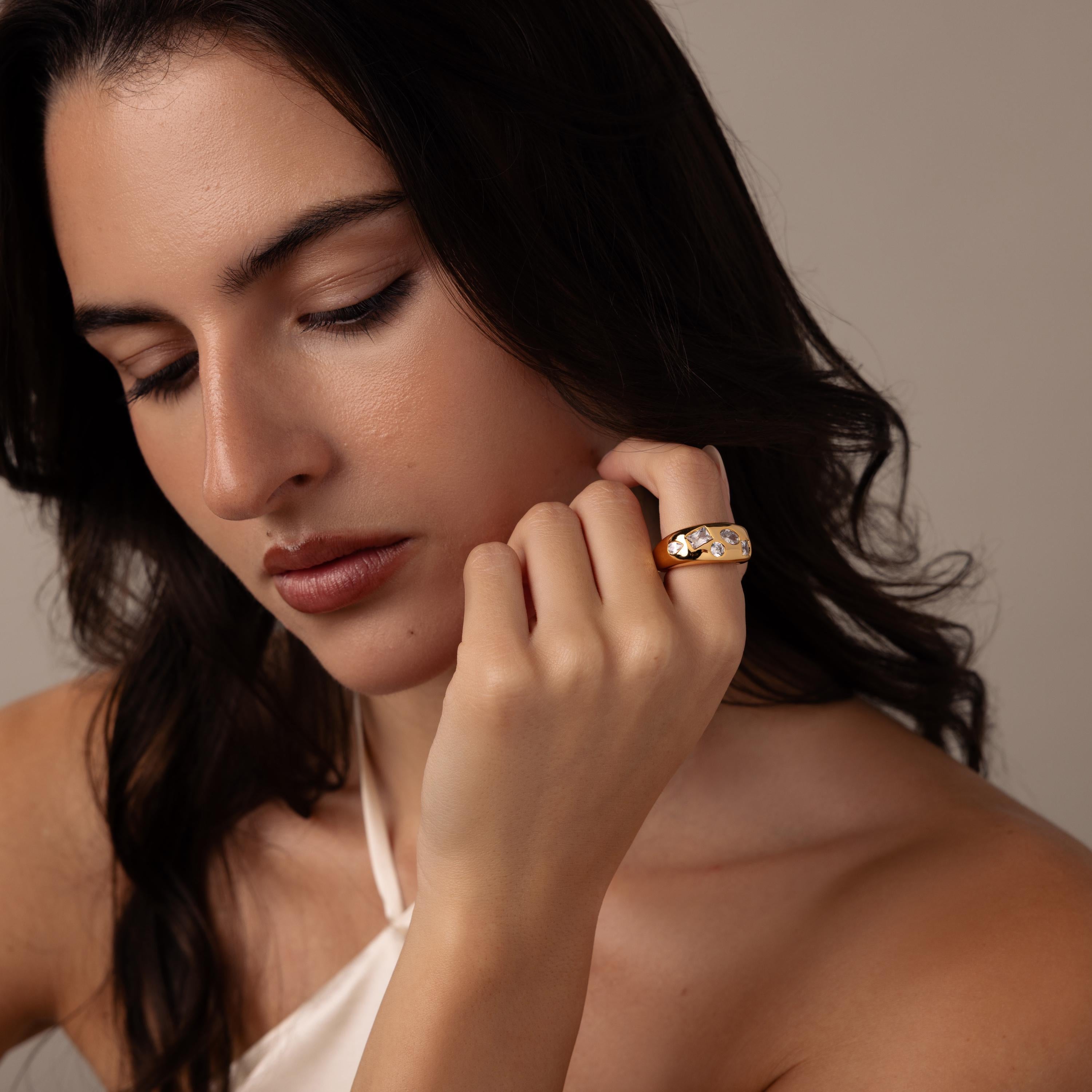 A woman with long dark hair gazes down thoughtfully, wearing the Diamond Confetti Signet Ring in gold.