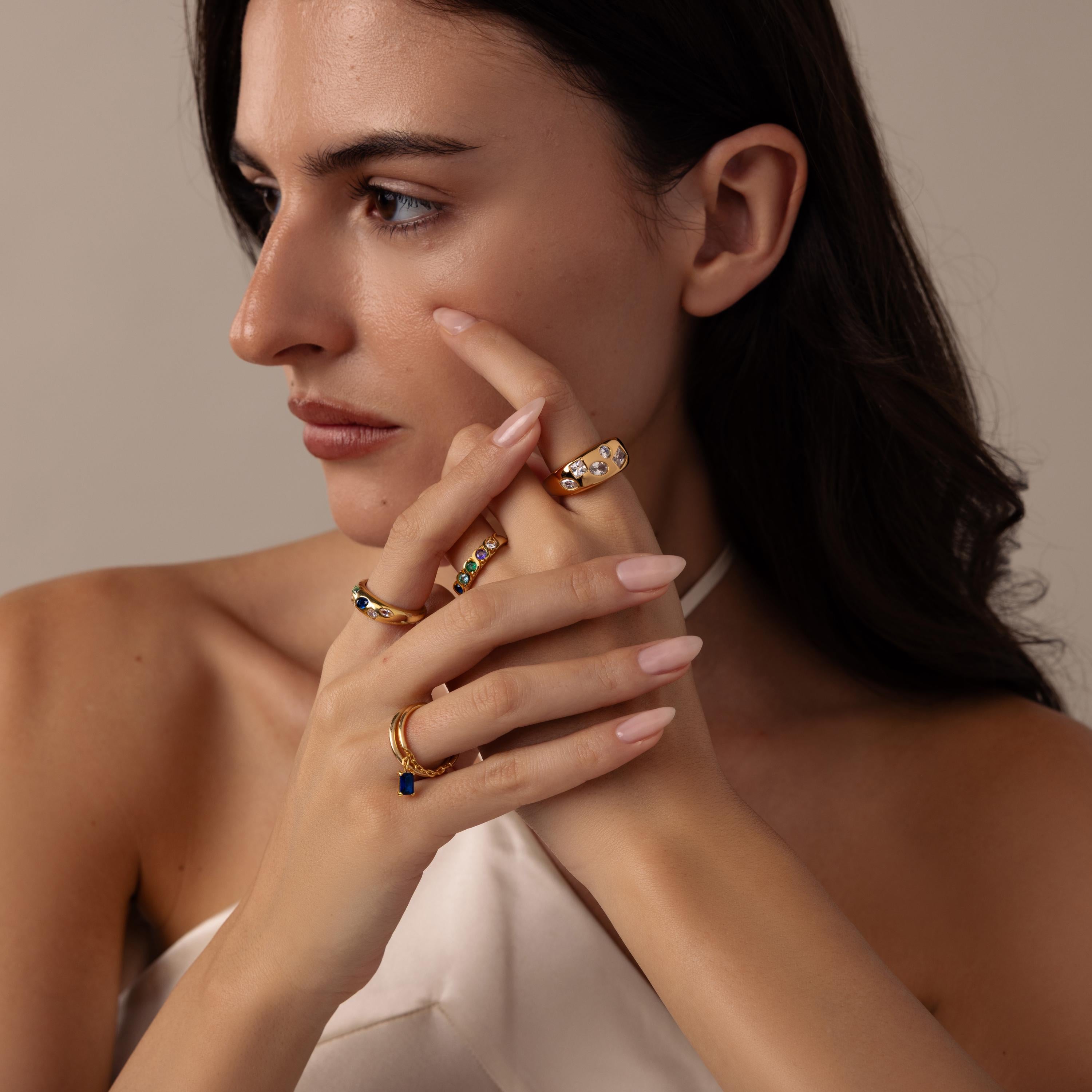 A woman in a white top poses with her hands near her face, showcasing several gold rings, including the elegant Diamond Confetti Signet Ring.
