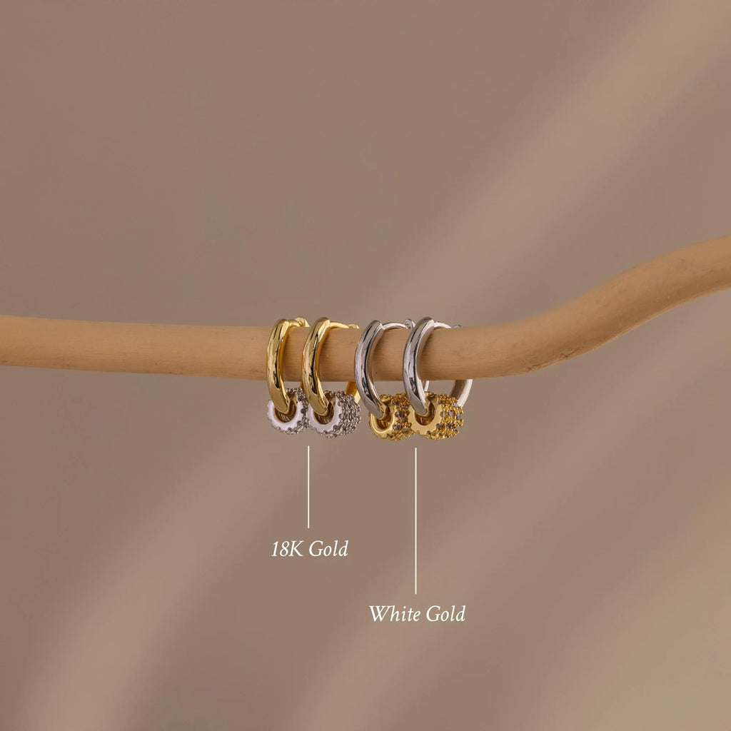 Our Mixed Metal Pave Hoops on a wooden stick with labels indicating '18K Gold' and 'White Gold' against a brown background.