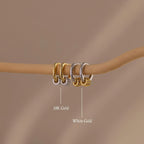 Our Mixed Metal Pave Hoops on a wooden stick with labels indicating '18K Gold' and 'White Gold' against a brown background.
