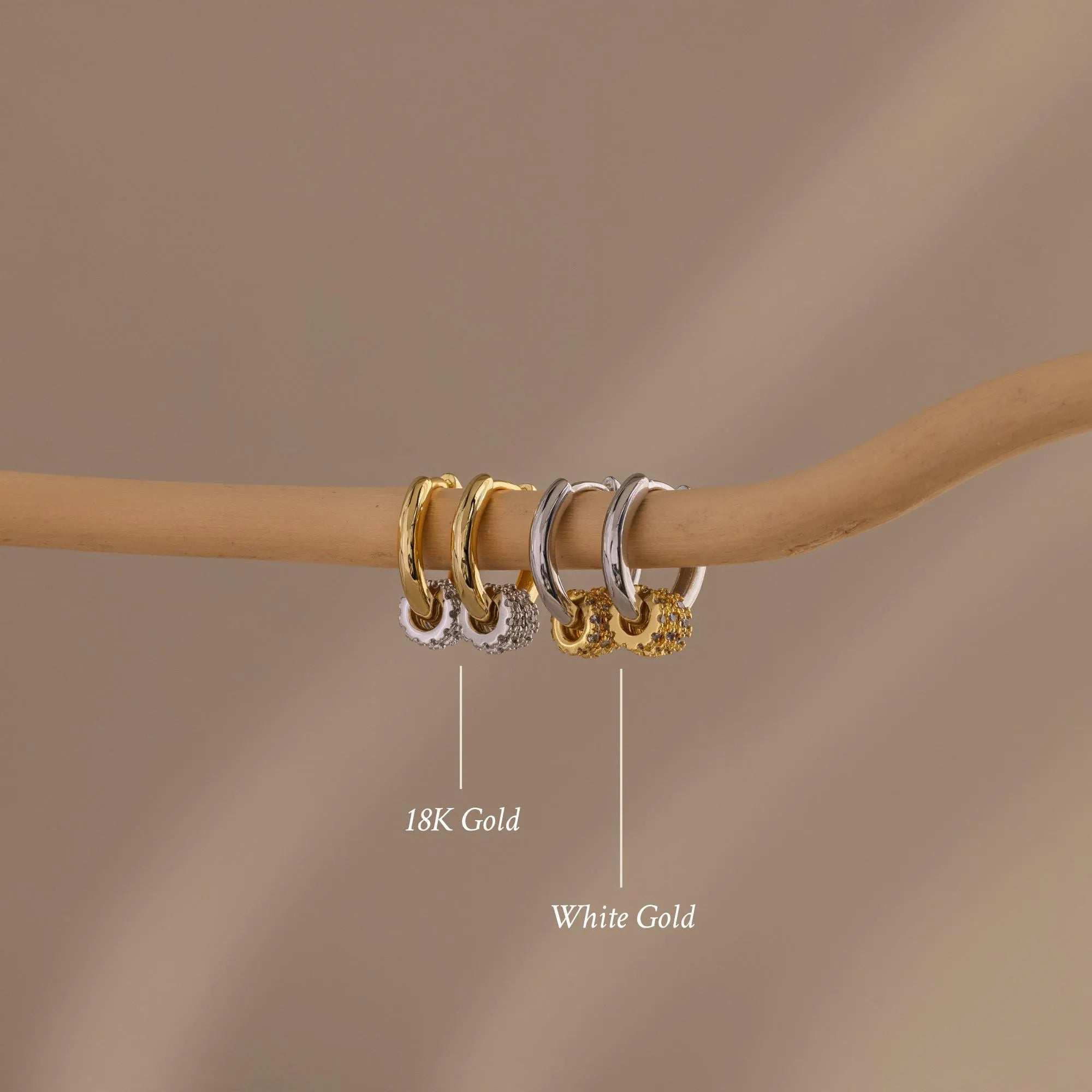 Our Mixed Metal Pave Hoops on a wooden stick with labels indicating '18K Gold' and 'White Gold' against a brown background.
