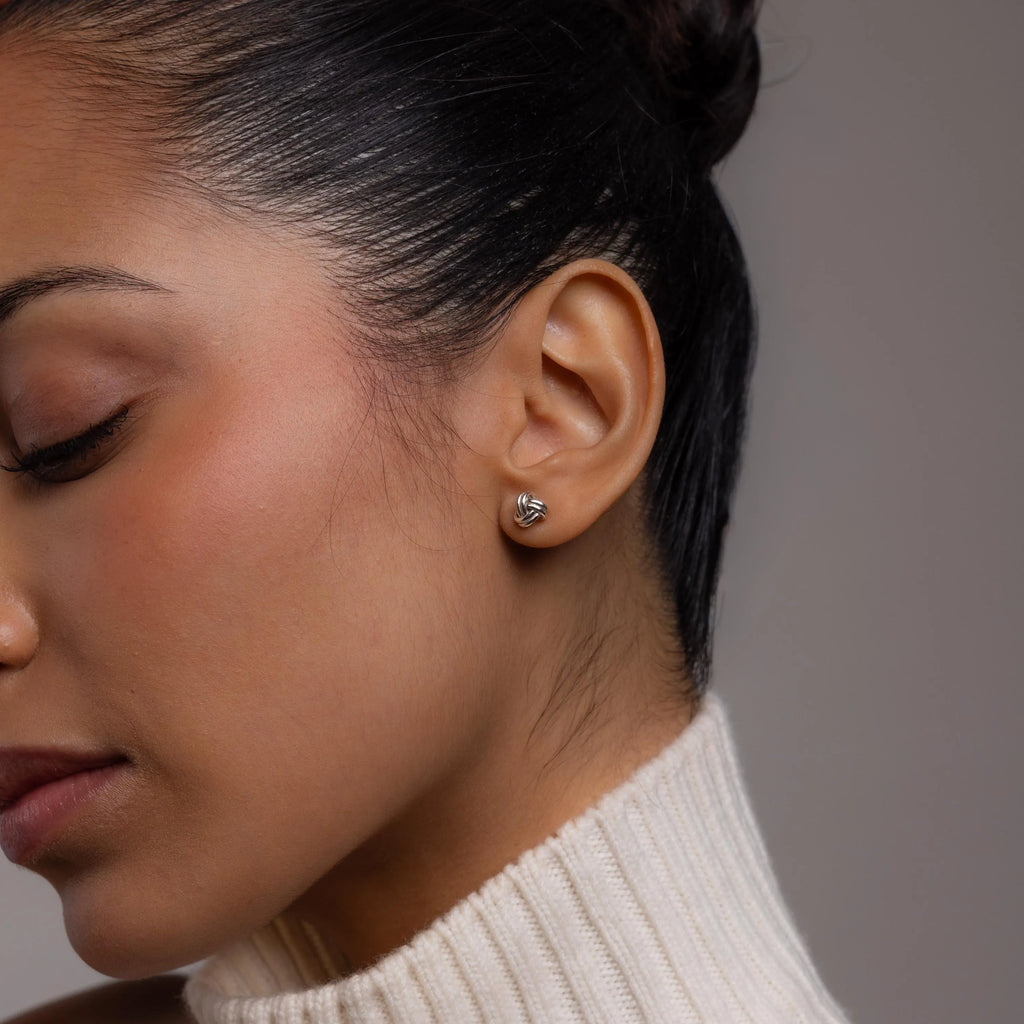 Close-up of a woman wearing a diamond earring against a neutral background