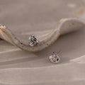 Silver knot earrings on a textured beige surface