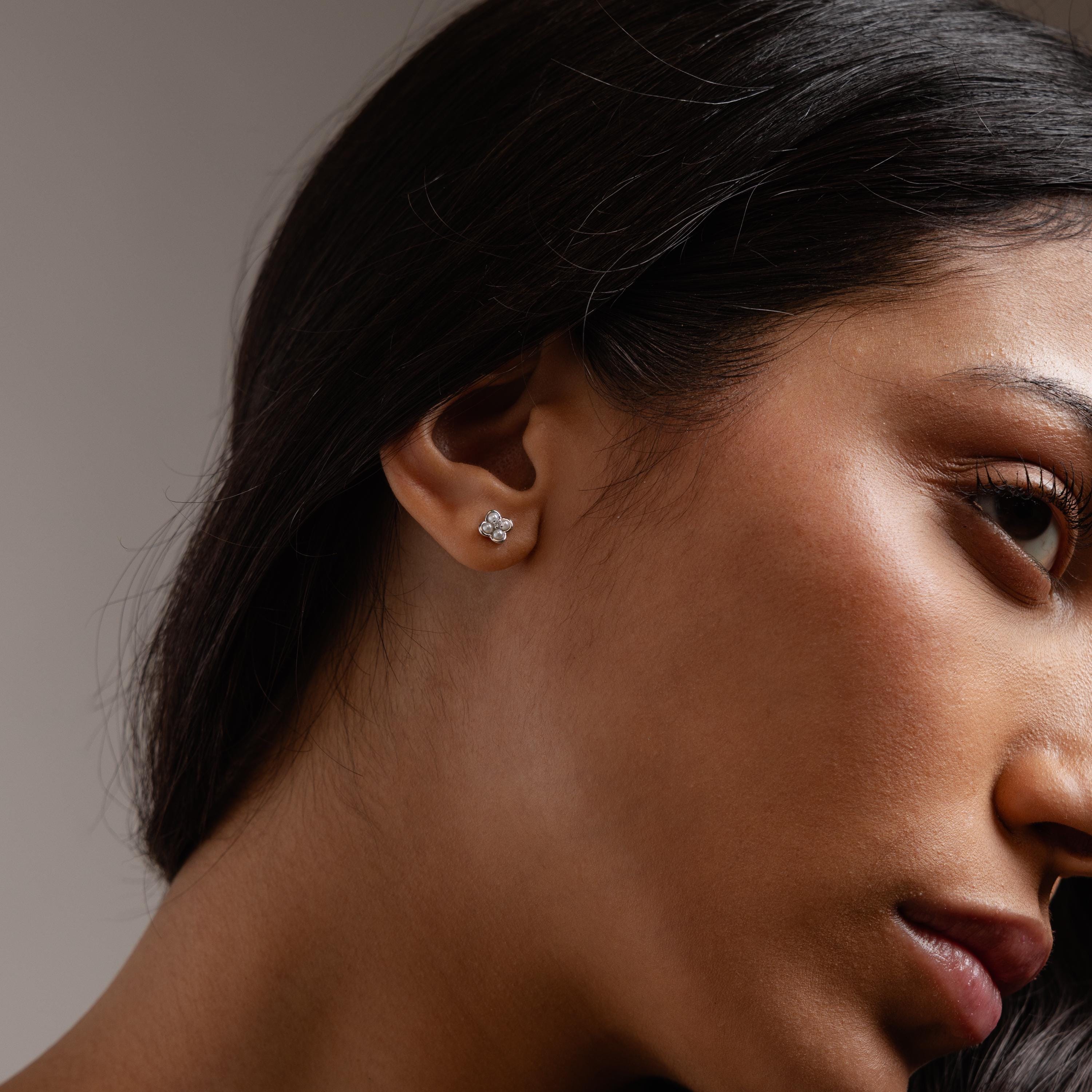 Close-up of a woman wearing Rounded Pearl Flower Studs—floral-shaped earrings with pearls, perfect as bridesmaid jewelry or for pairing with other elegant stud earrings.