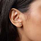 Close-up of a woman's ear wearing Rounded Pearl Flower Studs—featuring a gold floral design with white stones, making them perfect as elegant bridesmaid jewelry.