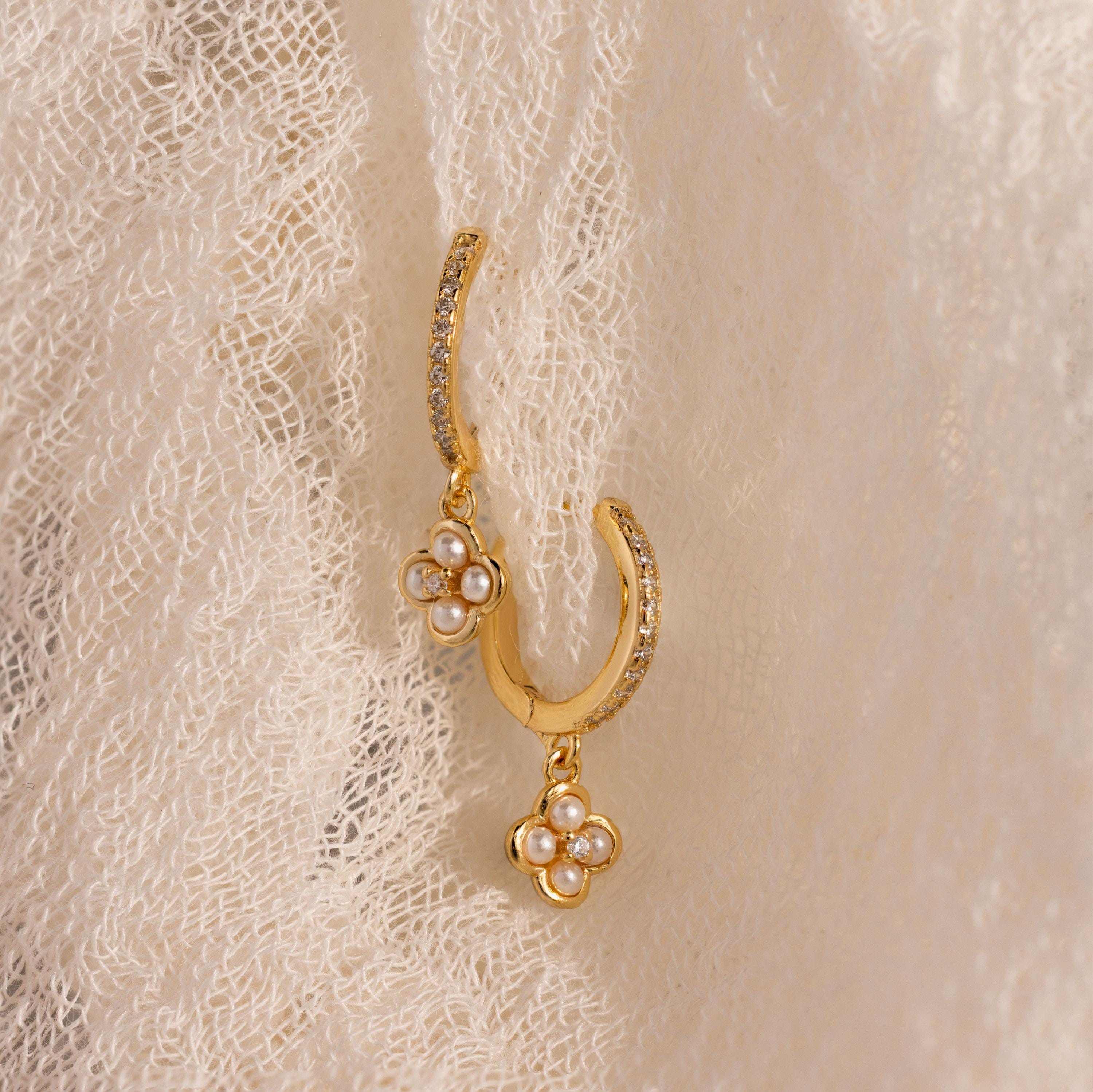 Pave Rounded Pearl Flower Hoops in 18K Gold, shown on textured cream fabric, feature delicate pearl flower charms—ideal for weddings or adding elegance to classic hoop earrings.