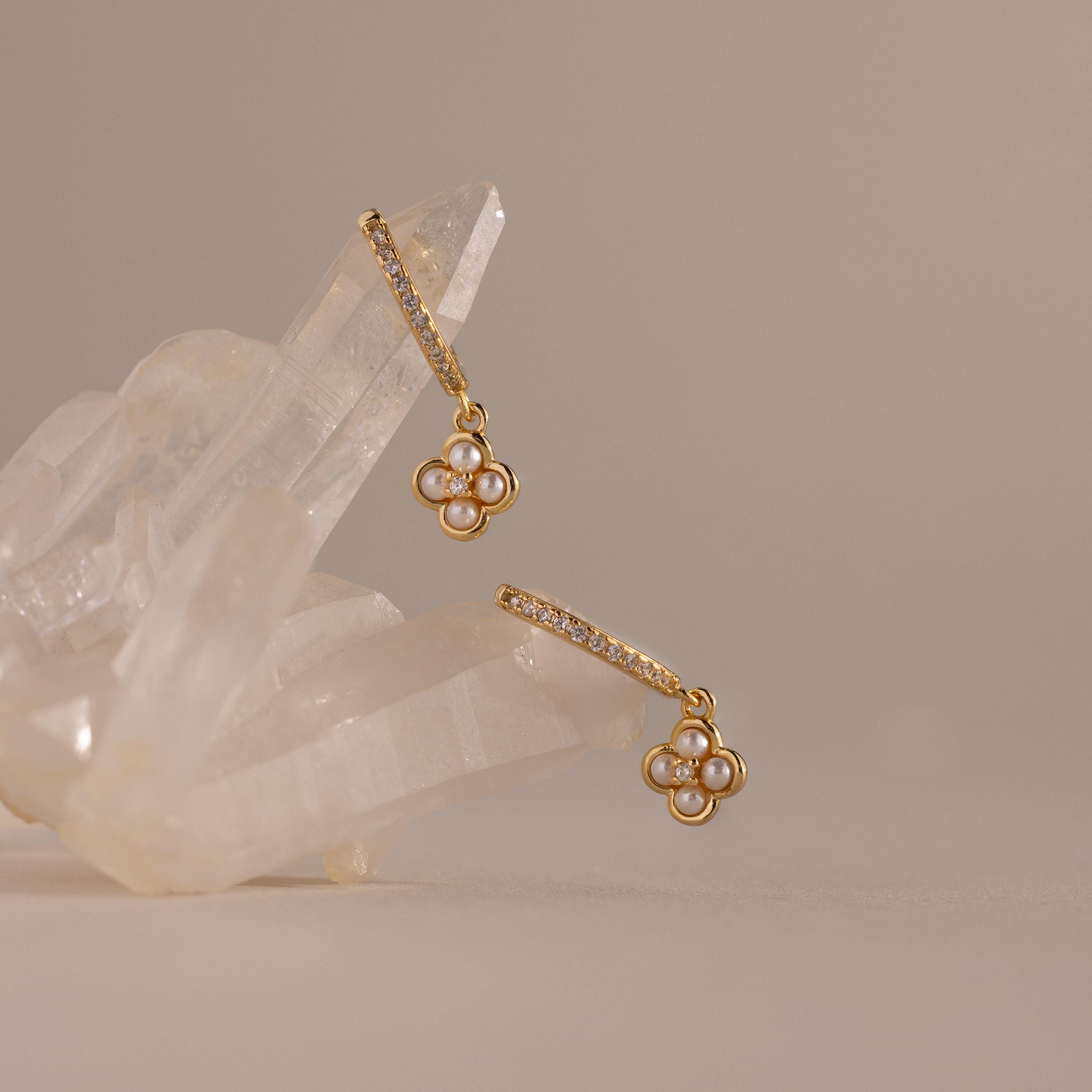 The Pave Rounded Pearl Flower Hoops in 18K Gold feature pearl flower charms and crystal accents, displayed on clear quartz crystals—perfect as elegant wedding earrings.