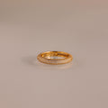The Skinny Pave Stacking Ring, featuring three rows of sparkling pave stones, rests elegantly on a light-reflective surface.