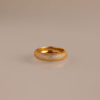 The Bold Pave Stacking Ring, encrusted with small diamonds, gleams on a reflective beige surface.