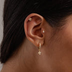 Close-up of an ear adorned with Rounded Pearl Flower Studs in 18K Gold and other elegant earrings—ideal for bridesmaid jewelry.