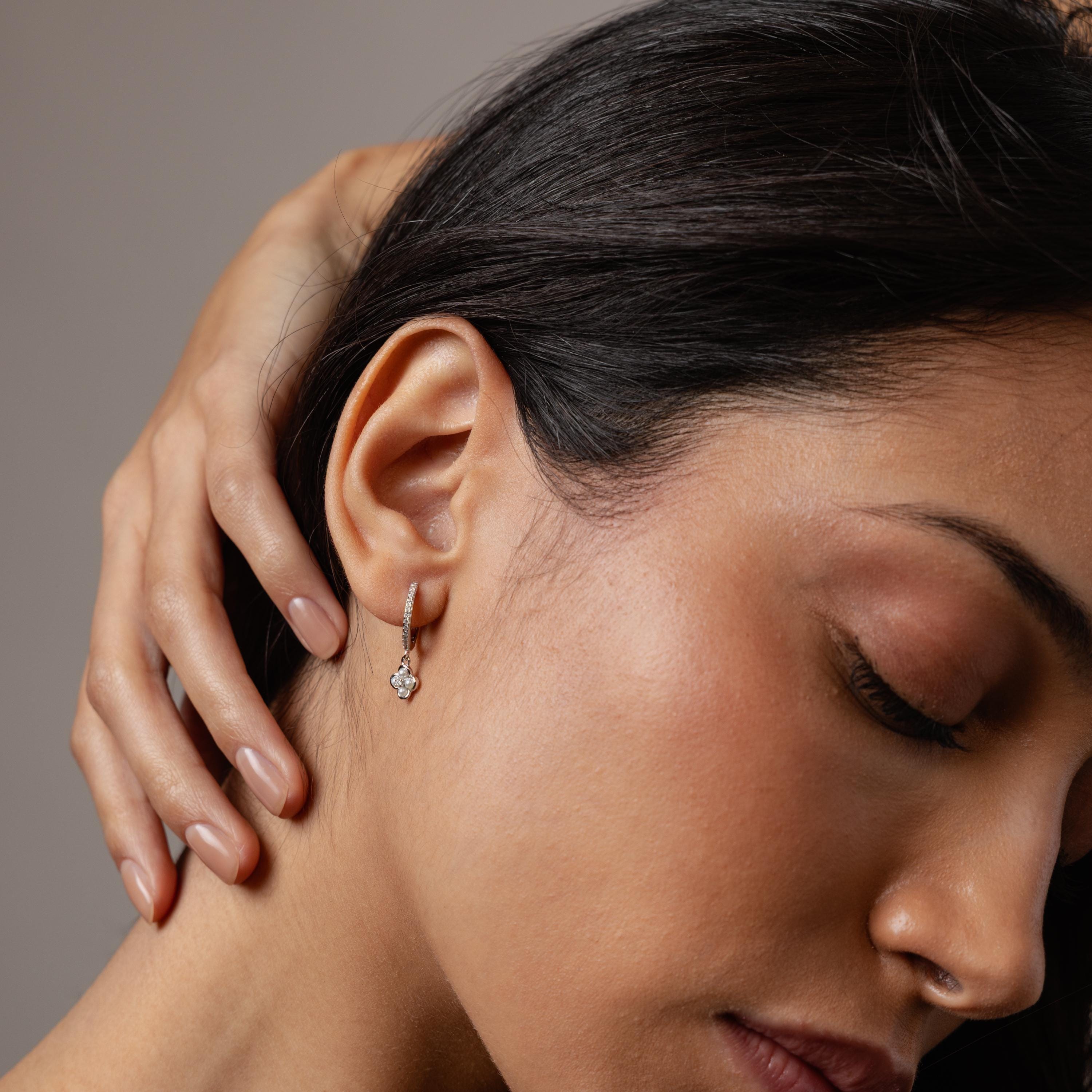 With her eyes closed and hand on her neck, she wears Pave Rounded Pearl Flower Hoops, adding a romantic touch to her look.