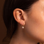Close-up of a woman's ear wearing Round Pearl Hoops in gold, each featuring a small dangling pearl—an elegant and timeless jewelry piece.