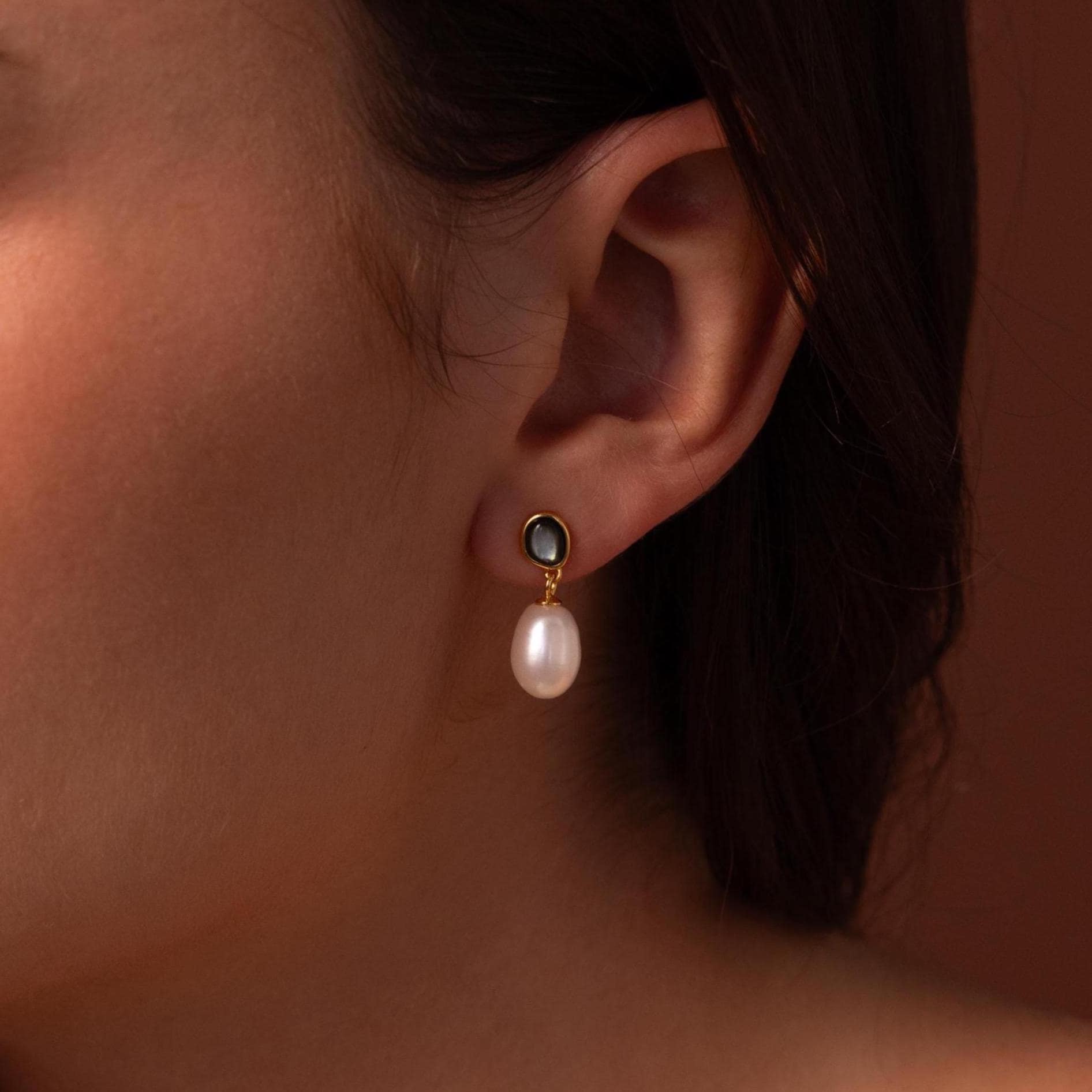 A close-up of a woman's ear wearing Midnight Pearl Drop Earrings, highlighting their elegant and timeless jewelry style.