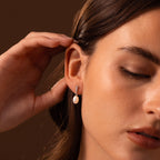 A woman with her hand on her ear, showcasing the elegant Diamond Pearl Droplet Earrings in Sterling Silver.