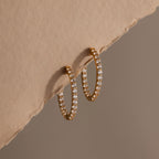 Inside Out Diamond Hoops in 18k gold with small diamonds, showcased on a textured beige surface and a soft brown backdrop.