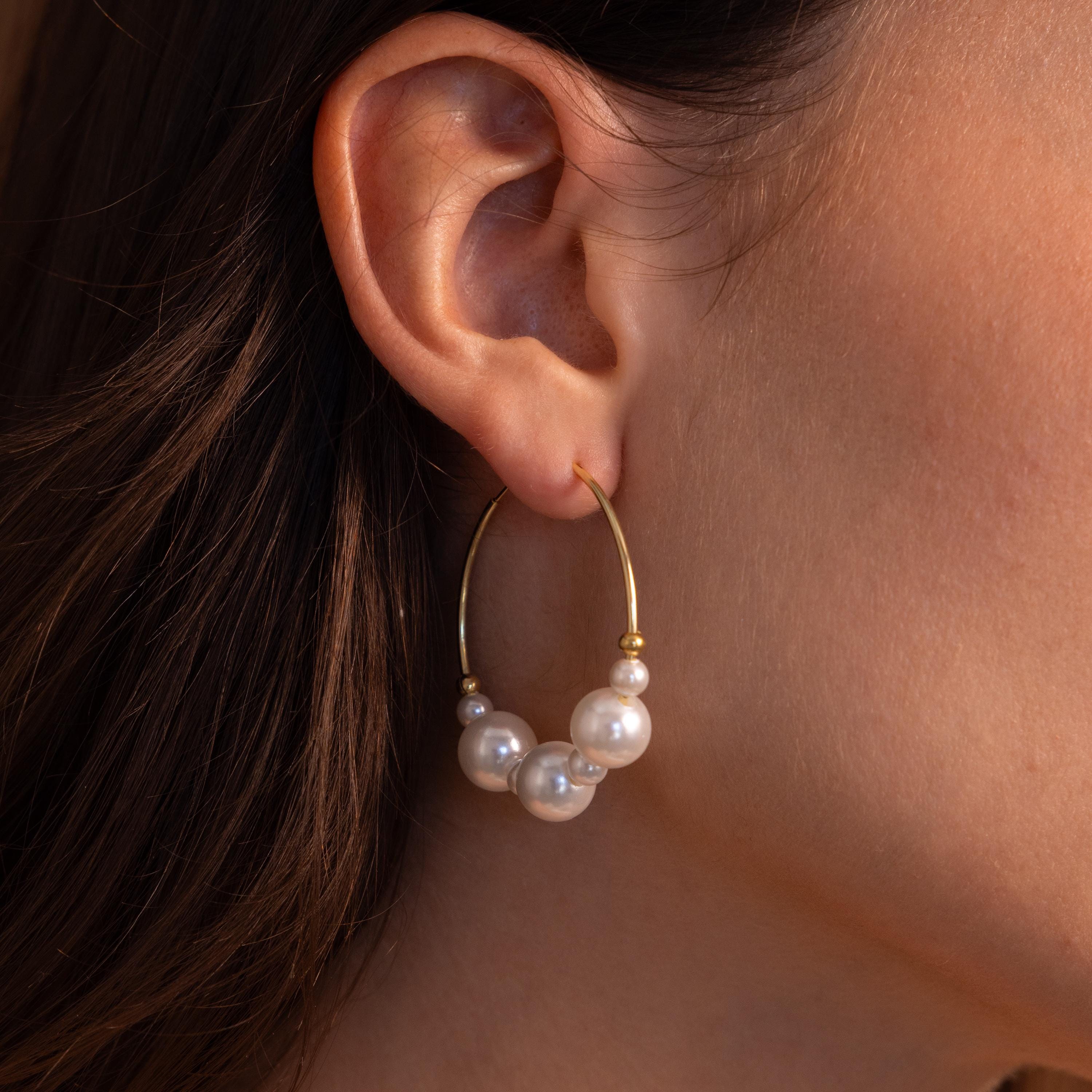 Close-up of a woman's ear adorned with Statement Pearl Hoops in 18K Gold, featuring elegant white pearl beads that embody quiet luxury.