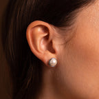 Close-up of a woman’s ear wearing Pearl Bezel Studs in Sterling Silver, highlighting the modern elegance of these round pearl earrings.