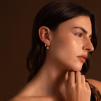 Woman with long brown hair wears timeless Round Pearl Hoops, posing against a brown background.