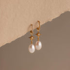 North Star Pearl Hoops featuring elegant pearl drops and star details, showcased on a textured beige surface.