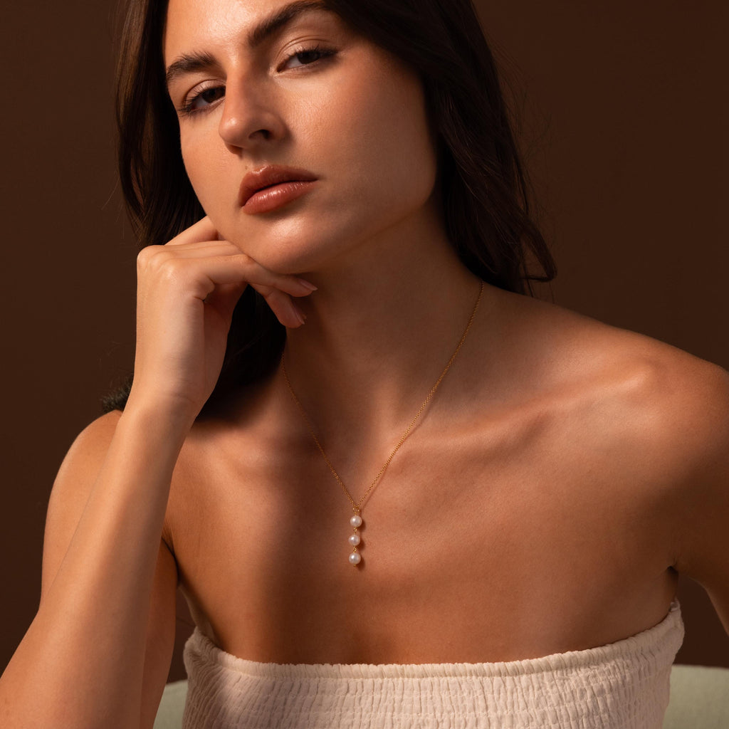 A woman posing for a picture, her neckline beautifully highlighted by the elegant Pearl Cascade Necklace.