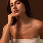 A woman posing for a picture, her neckline beautifully highlighted by the elegant Pearl Cascade Necklace.
