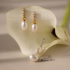 Diamond Pearl Droplet Earrings are displayed on a white calla lily under soft lighting, highlighting their elegant drop design.