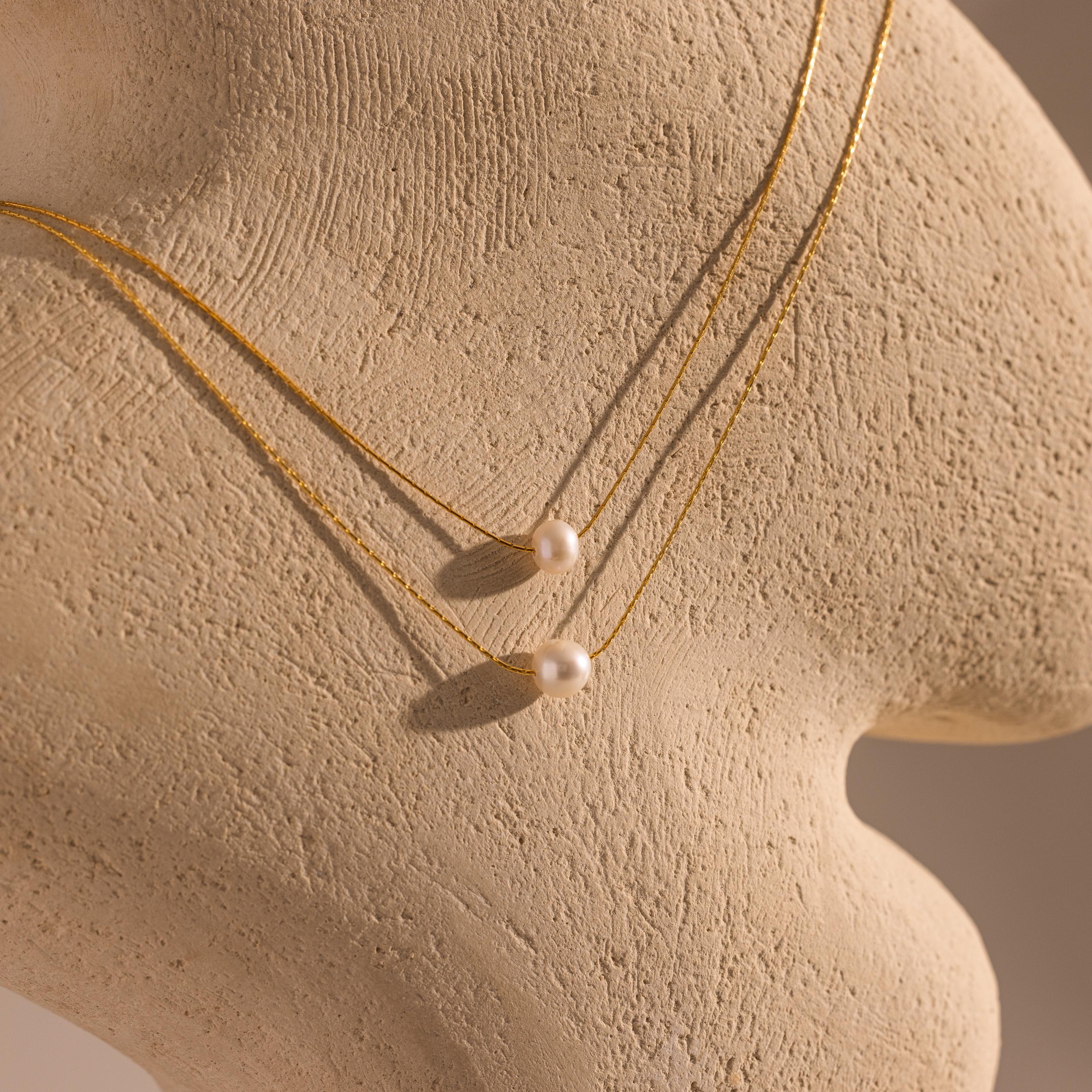 The Pearl Dot Necklace is displayed on a textured beige mannequin bust.