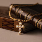 The Majesty Cross Necklace in 18K Gold, adorned with shimmering diamonds, rests gracefully on leather-bound vintage books, embodying timeless faith jewelry.