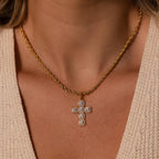 The Majesty Cross Necklace in 18K Gold, featuring a diamond-encrusted pendant, shines elegantly on a woman in a beige textured top—a stunning piece of faith jewelry.