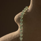 A Jade Choker Necklace in Silver drapes elegantly over a textured, abstract sculpture resembling a human torso.
