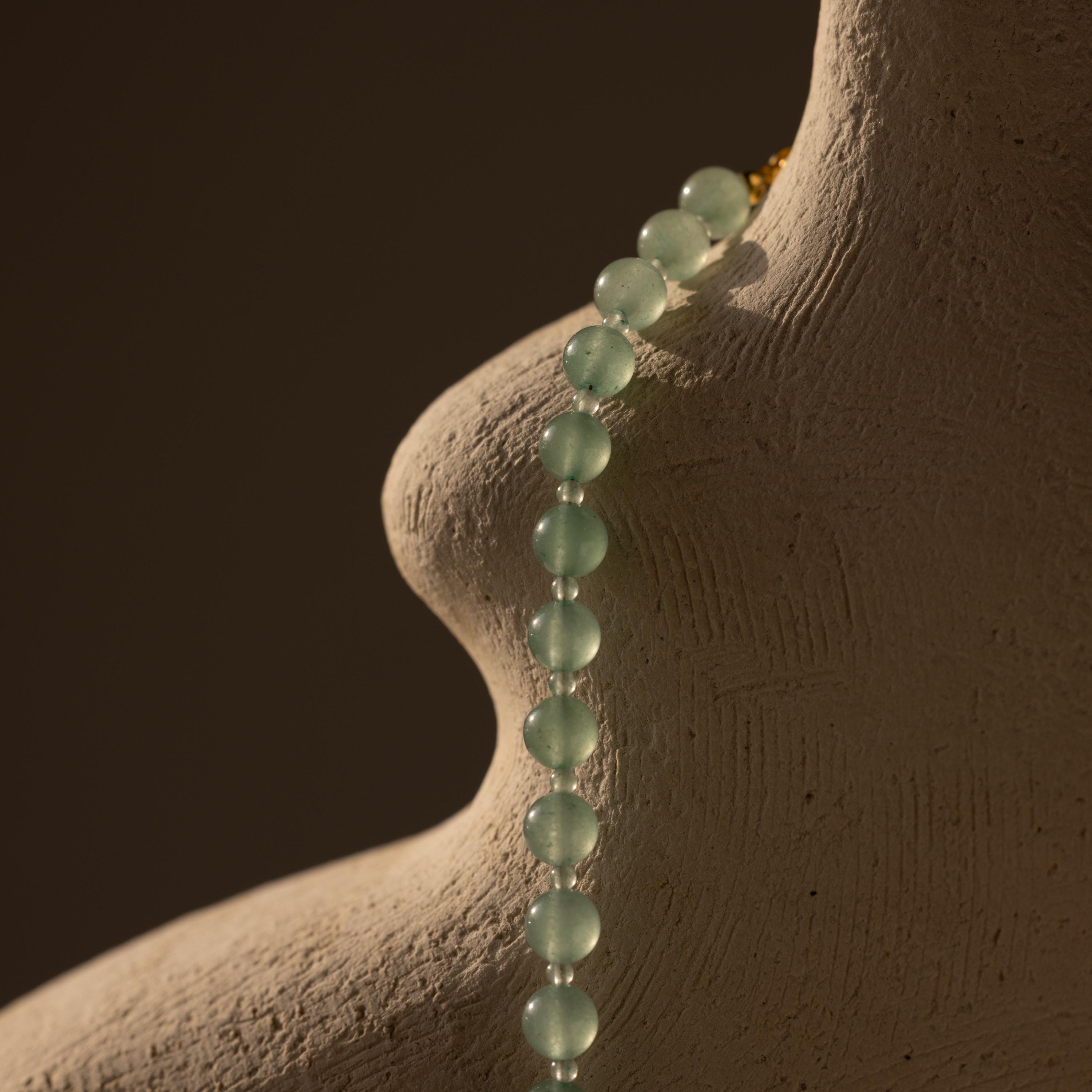 A Jade Choker Necklace in Silver drapes elegantly over a textured, abstract sculpture resembling a human torso.