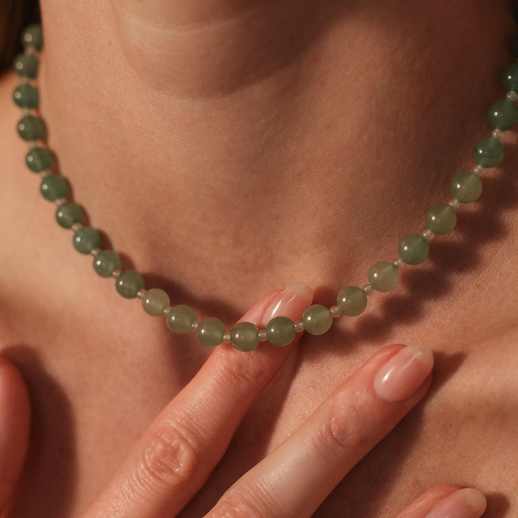 Close-up of a person wearing the Jade Choker Necklace in Silver, gently touching it with neatly manicured fingers.