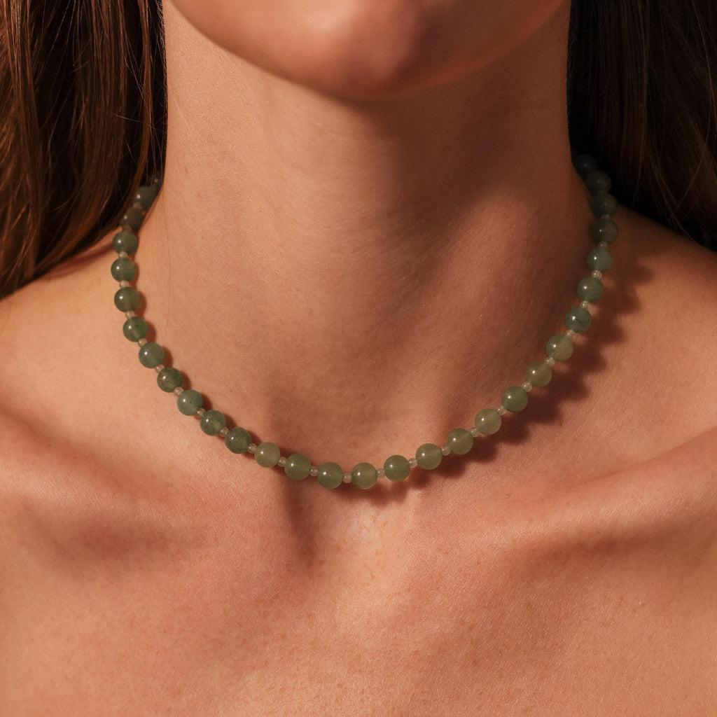 A woman wears the Jade Choker Necklace—a green beaded piece—close up on her neck and collarbone.