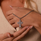 Woman wearing the Majesty Cross Necklace in Silver, featuring sparkling stones, paired with a cream knit top and a nude manicure.