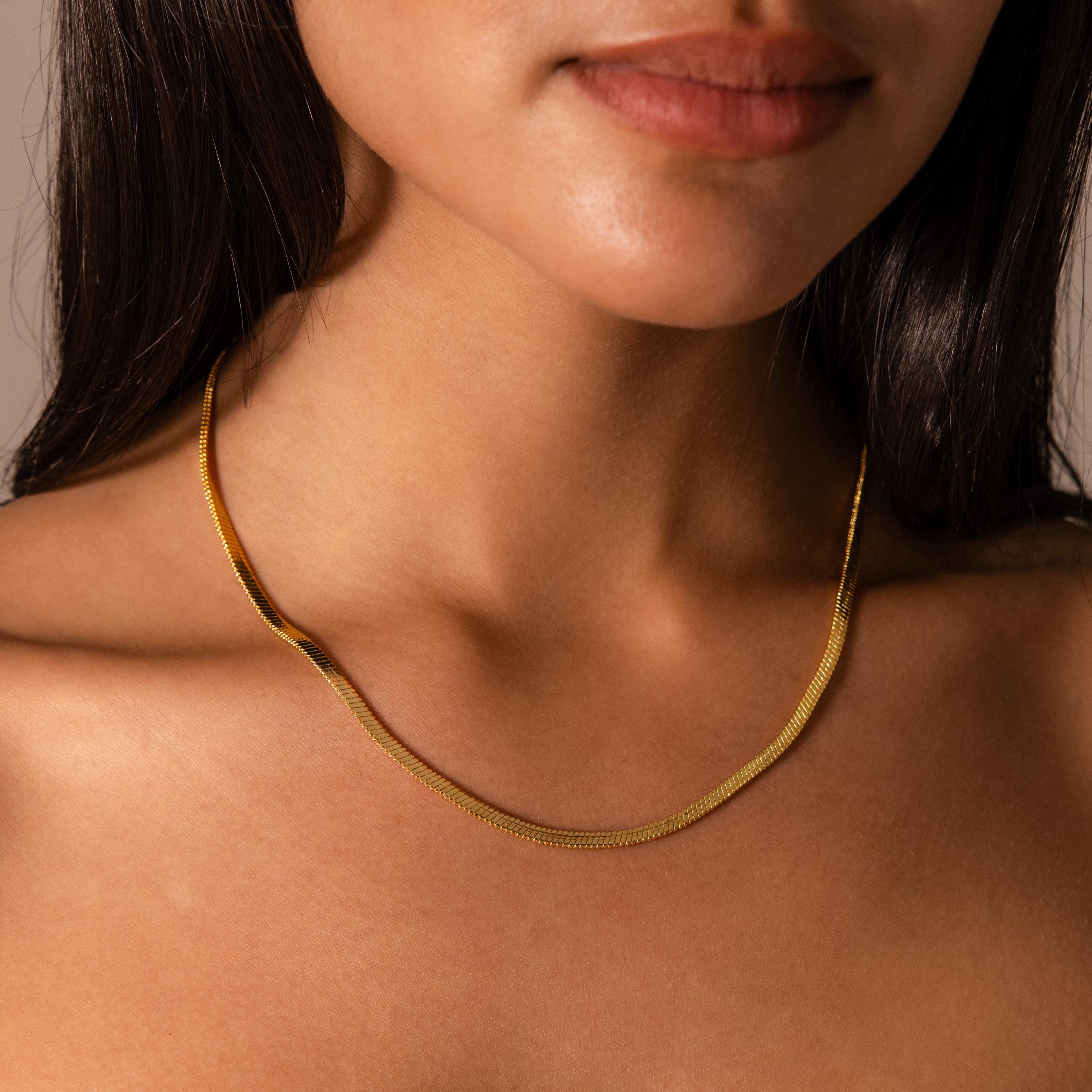 A woman wears the Twisted Snake Chain Necklace against her bare neck and shoulders, showcasing a modern and minimal necklace style.