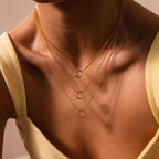 A woman wears a cream top and the Cable Circle Charm Necklace in 18K Gold, a statement piece with three layered gold cables and circular pendants.