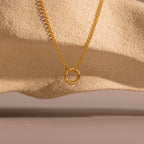 Cable Circle Charm Necklace shown on textured beige stone with soft shadows; a versatile piece ideal for layering and adding effortless elegance to any look.