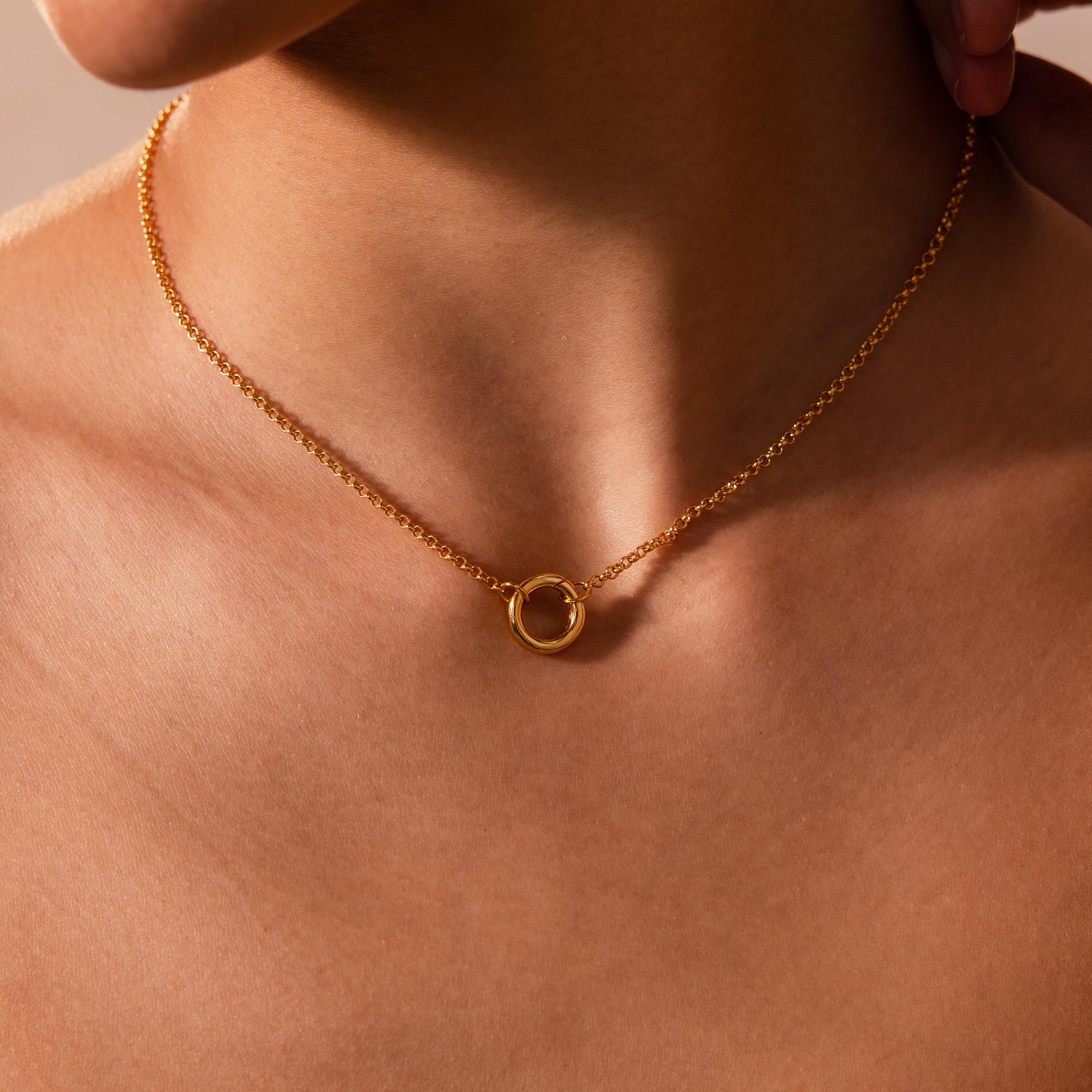 The Cable Circle Charm Necklace features a gold circular pendant, ideal for wearing on bare skin as a subtle layering piece or as a chic statement accessory.