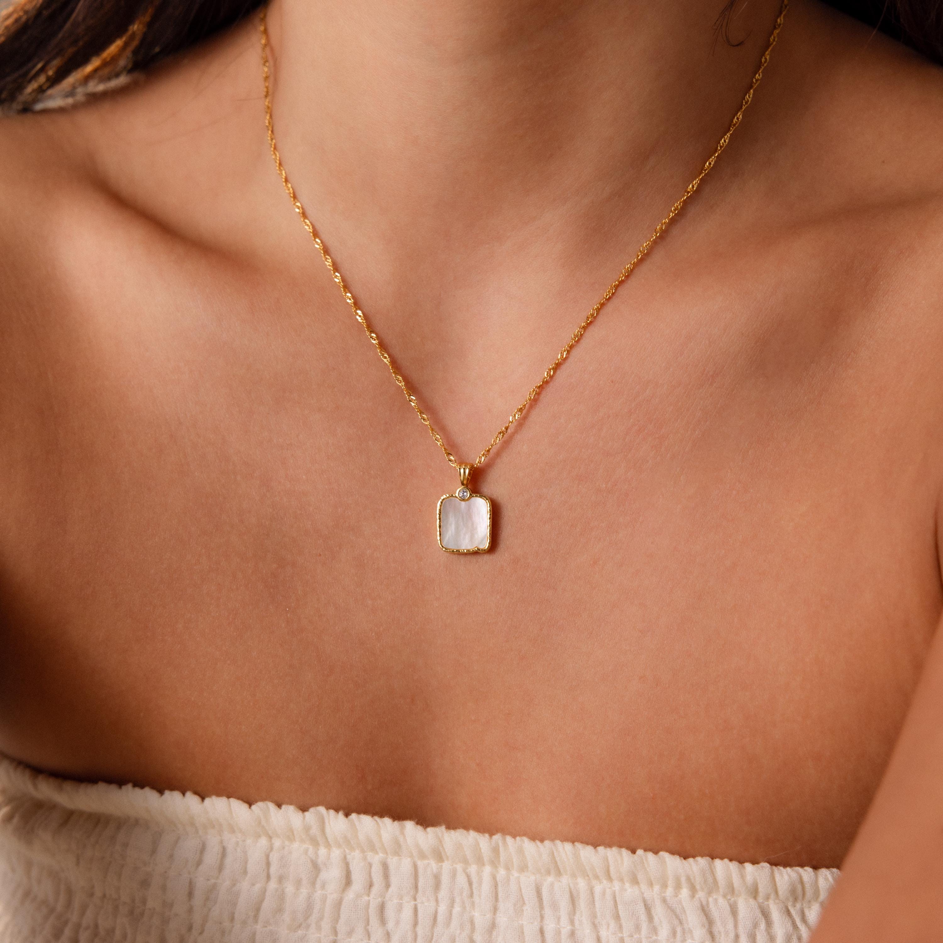Close-up of a woman in a white top wearing the Square Mother of Pearl Necklace, with a delicate gold chain and an iridescent square pendant.