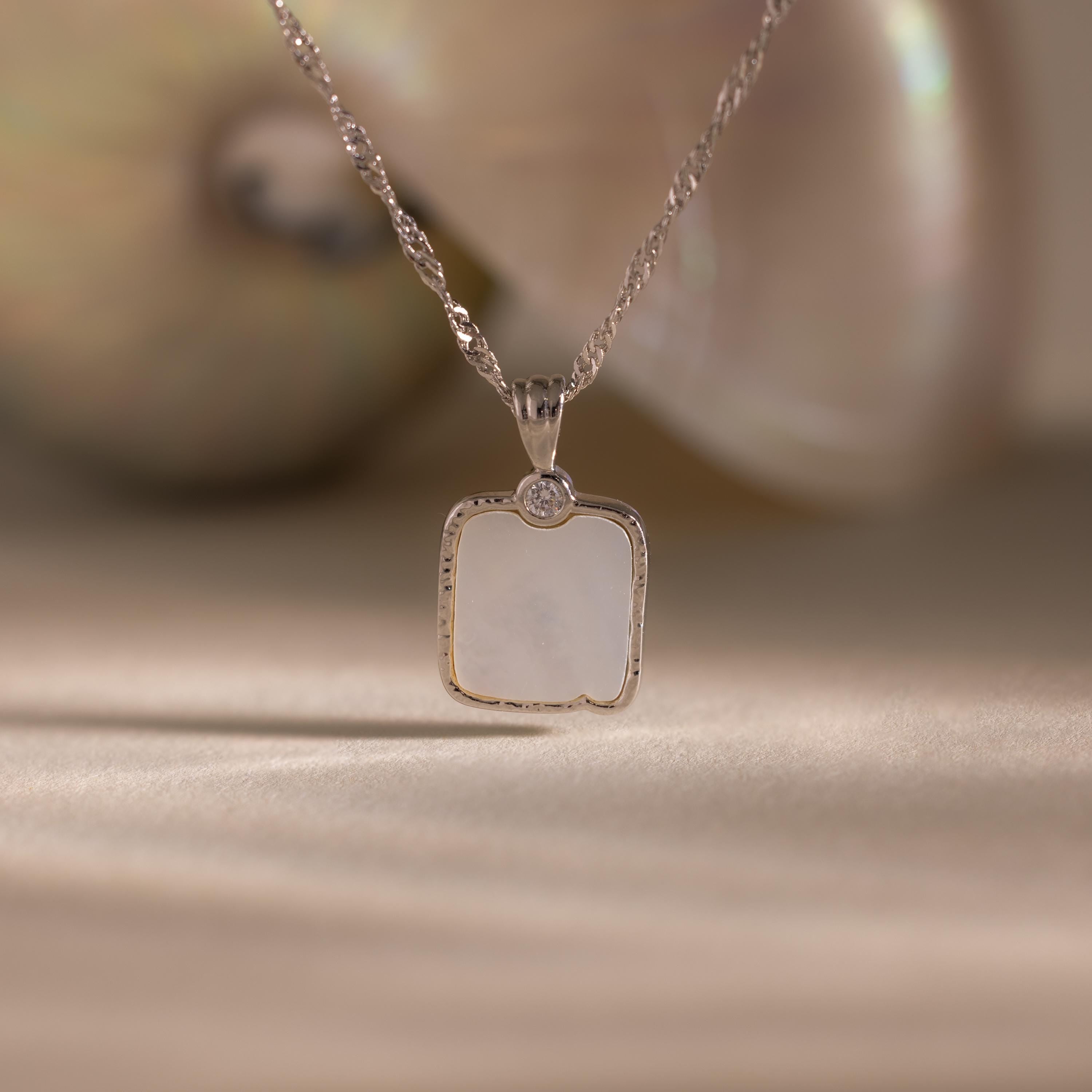 Square Mother of Pearl Necklace in Silver features an iridescent pendant with a diamond accent, beautifully displayed against a soft background—perfect for layering.