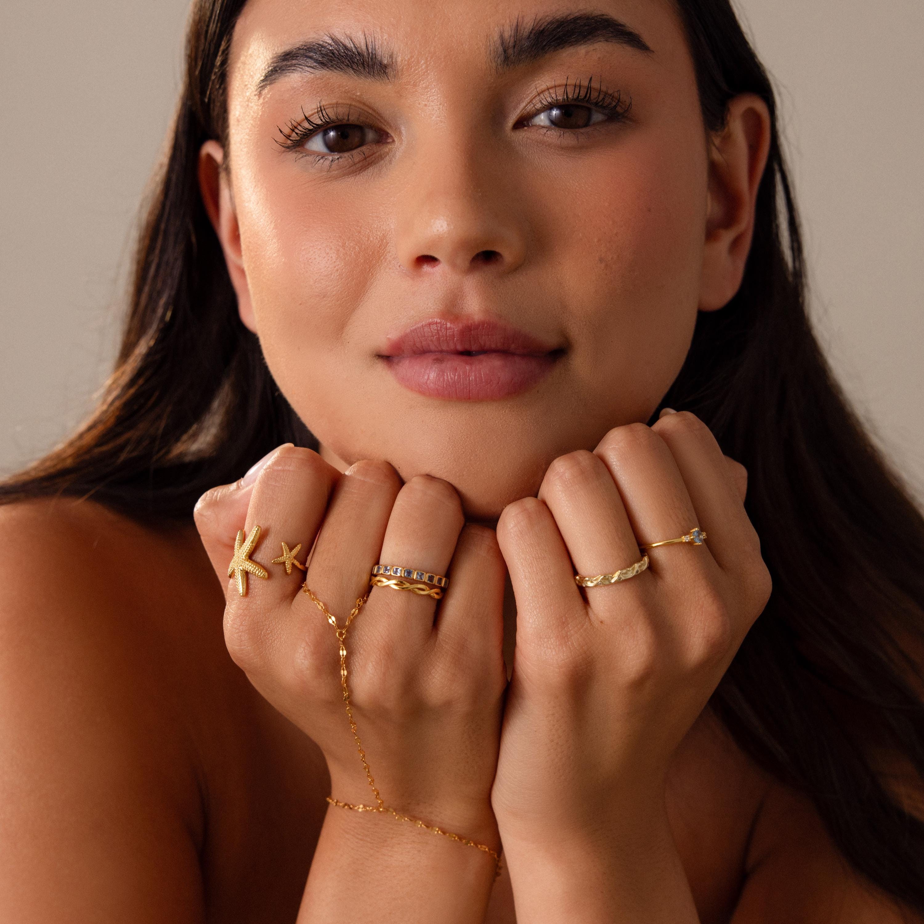 Woman with long dark hair displays a statement gold hand chain and the Open Duo Starfish Ring, hands gently pressed to her chin for a coastal-inspired look.