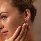 Woman with light skin and green eyes wearing Ombre Birthstone Flatback Studs, touching her face gently—a perfect choice for a personalized gift.